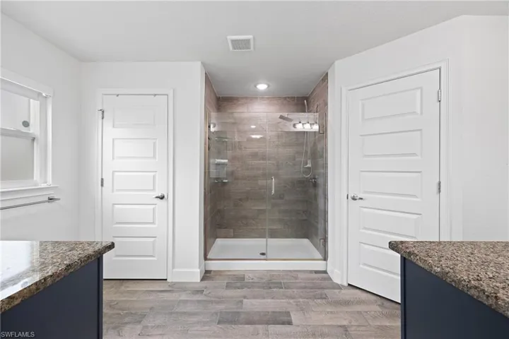 Bathroom featuring vanity, a stall shower, and light wood finished floors