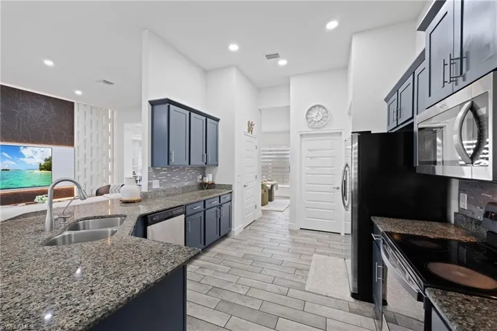 Kitchen featuring stainless steel appliances, dark stone countertops, wood finish floors, a peninsula, and recessed lighting