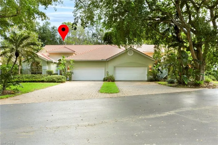 View of front of property with a tile roof, paver driveway, and attached double garage