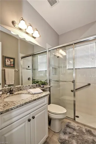 Bathroom featuring tile patterned flooring, vanity, toilet, and an enclosed shower