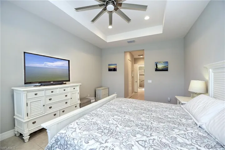 Tiled bedroom with ceiling fan and a raised ceiling