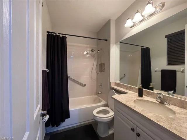 Full bathroom with vanity, shower / bathtub combination with curtain, and toilet