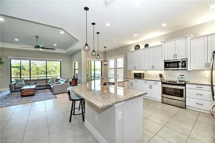 Kitchen featuring pendant lighting, a kitchen island with sink, white cabinets, ceiling fan, and stainless steel appliances
