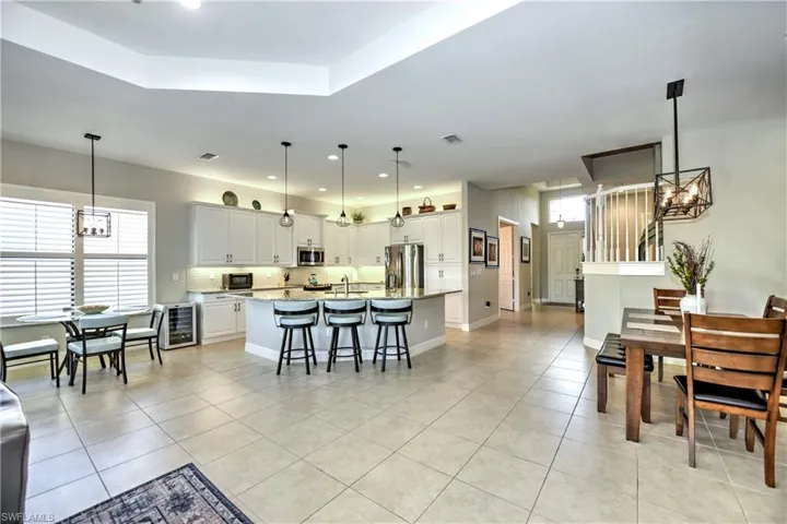 Kitchen featuring wine cooler, a chandelier, decorative light fixtures, a kitchen island with sink, and appliances with stainless steel finishes