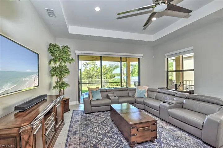 Tiled living room featuring a raised ceiling and ceiling fan