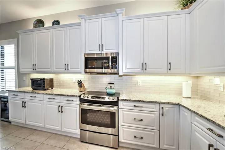 Kitchen with appliances with stainless steel finishes, light tile patterned floors, and white cabinetry