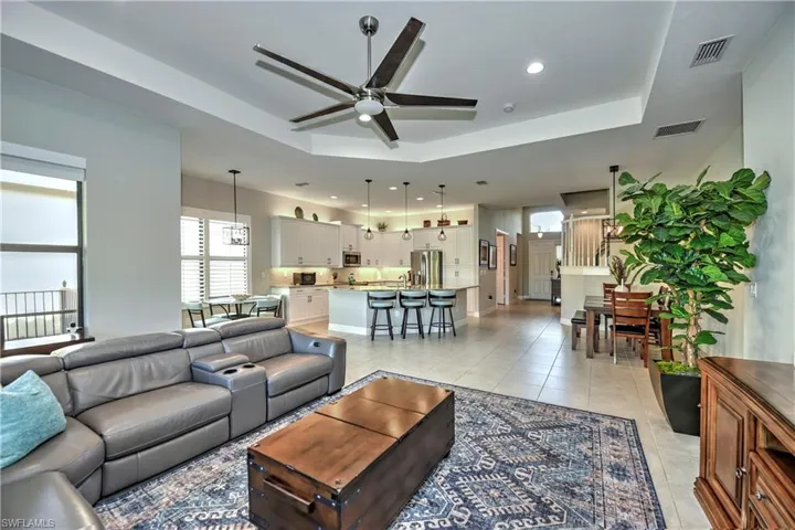 Living room featuring ceiling fan, light tile patterned flooring, and a tray ceiling