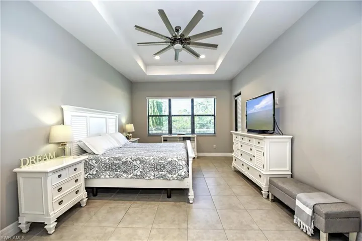 Bedroom with a raised ceiling, ceiling fan, and light tile patterned floors