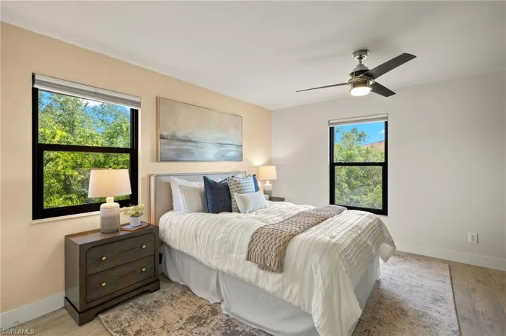 Bedroom with multiple windows, light wood finished floors, baseboards, and ceiling fan