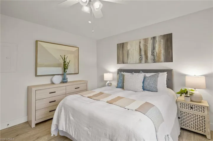 Bedroom featuring light wood-style floors, baseboards, ceiling fan, and electric panel