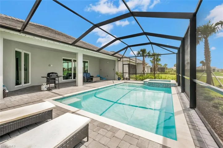 View of pool, hot tub, grilling area, and a lanai overlooking golf course with fabulous sunset view with western exposure