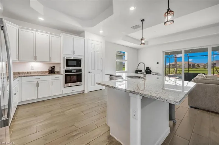 pendant lighting, sink, a tray ceiling, and appliances with stainless steel finishes along with gas range