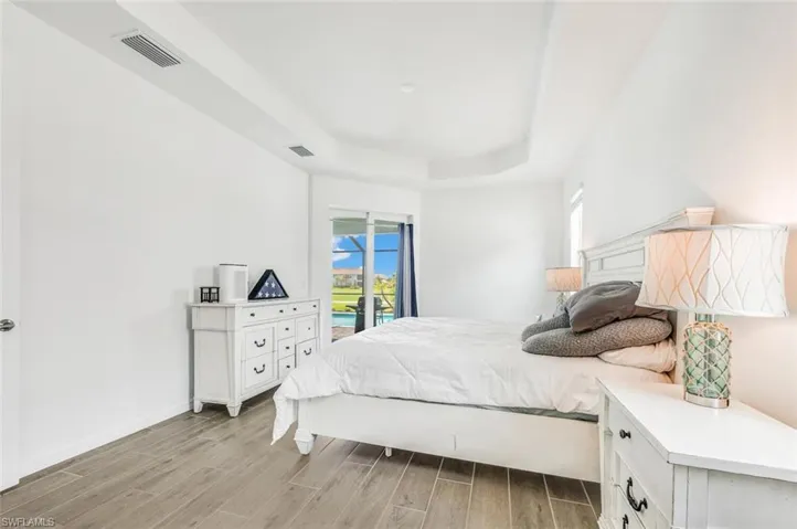Bedroom with light wood-type flooring, a tray ceiling, and access to exterior
