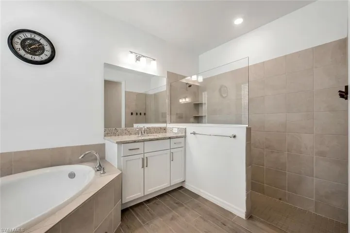 Bathroom with hardwood / wood-style floors, independent shower and bath, and vanity