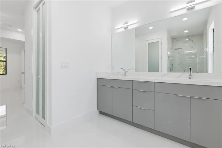 Bathroom with recessed lighting, double vanity, and a marble finish shower