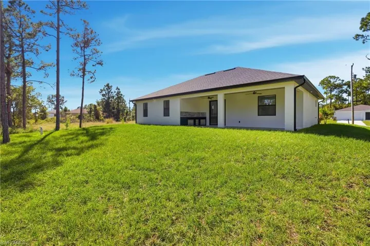 Back of house featuring a ceiling fan, a yard, a patio, stucco siding, and a shingled roof