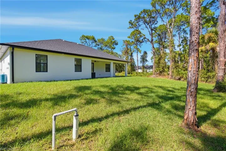 Back of house featuring stucco siding, a lawn, roof with shingles, and a patio