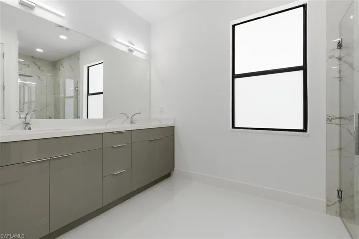 Full bath featuring a marble finish shower, double vanity, and recessed lighting