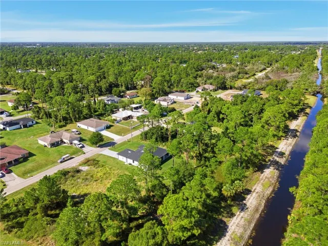 Aerial view of property and surrounding area with a large body of water and nearby suburban area