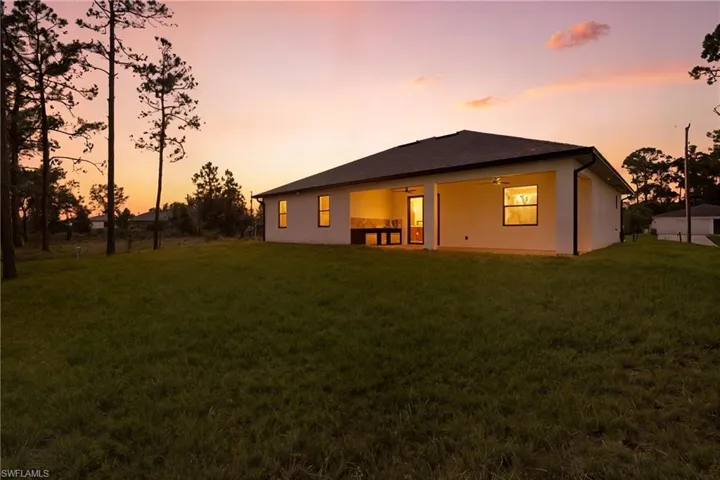 Back of property with a patio area, a ceiling fan, stucco siding, and a yard