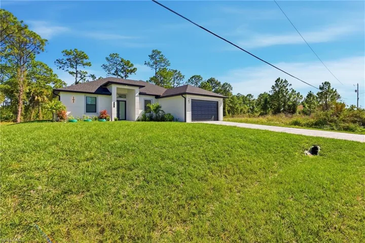 Prairie-style home with driveway, a front lawn, a garage, and stucco siding