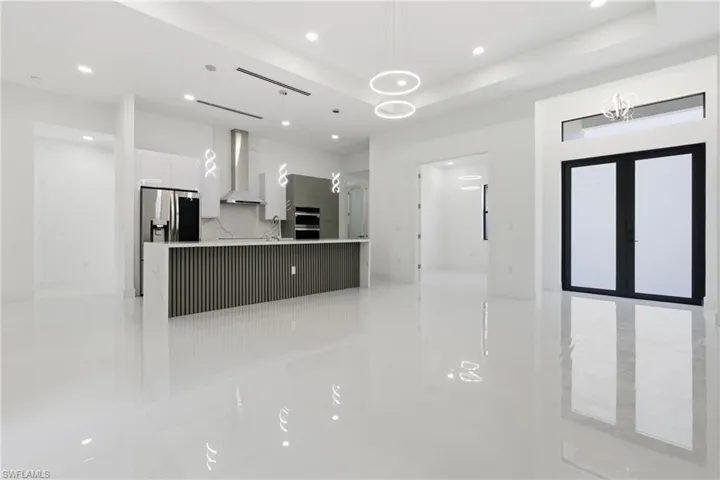 Kitchen featuring modern cabinets, white cabinetry, a large island, hanging light fixtures, and open floor plan