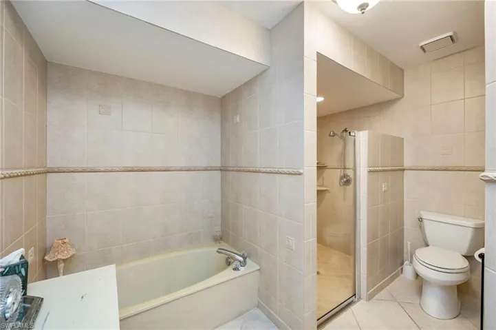 Bathroom with tile walls, a bath, a shower stall, and tile patterned flooring