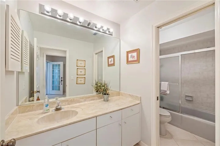 Bathroom with vanity, enclosed tub / shower combo, and light tile patterned floors