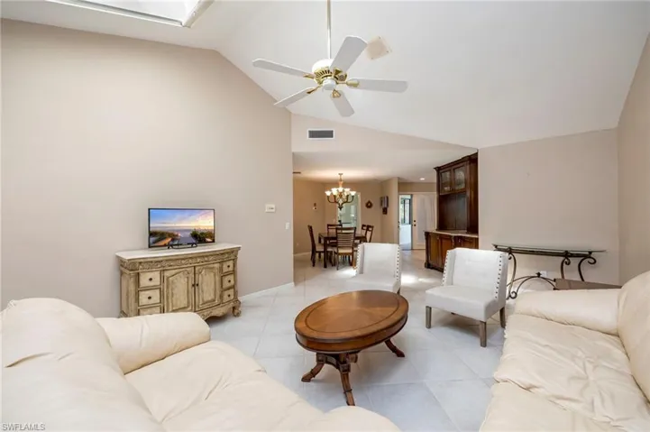 Living area with ceiling fan, lofted ceiling, light tile patterned flooring, and a chandelier