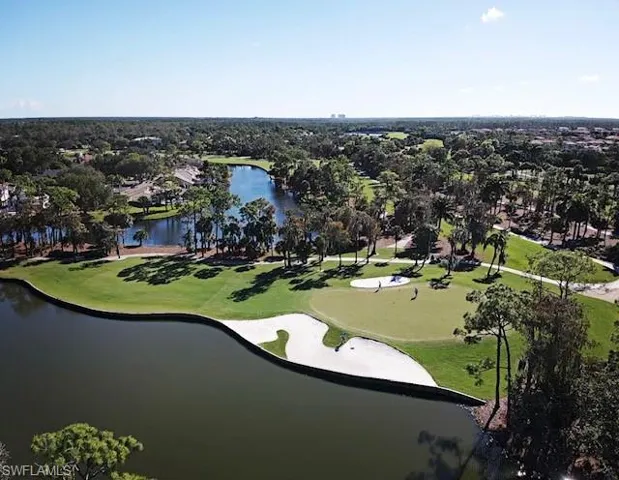 Aerial view of property and surrounding area with a local golf course, a nearby body of water, and nearby suburban area