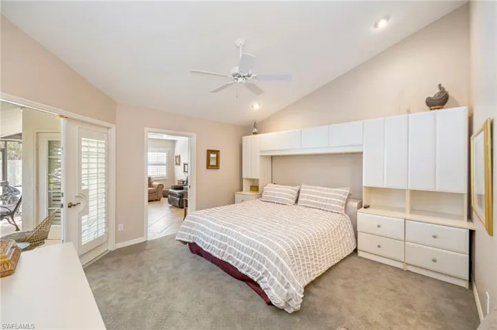 Bedroom with lofted ceiling, light carpet, and ceiling fan