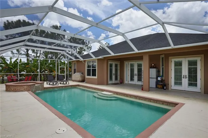 View of swimming pool featuring french doors, a patio area, a pool with connected hot tub, a lanai, and a grill