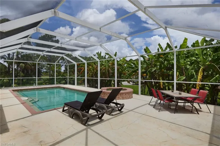 Swimming pool with a patio area, glass enclosure, and a jacuzzi