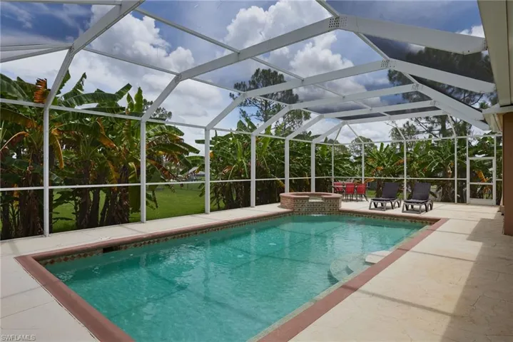 View of pool with a patio, a pool with connected hot tub, and glass enclosure