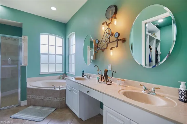 Bathroom featuring tile patterned flooring, a garden tub, double vanity, and a shower stall