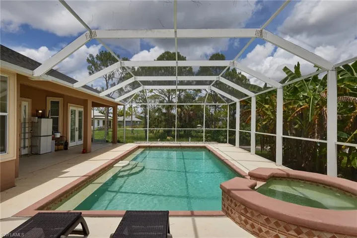 View of swimming pool featuring french doors, a patio area, a pool with connected hot tub, and a lanai
