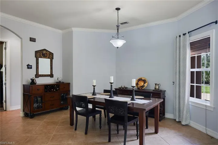 Dining area featuring arched walkways, ornamental molding, and light tile patterned floors