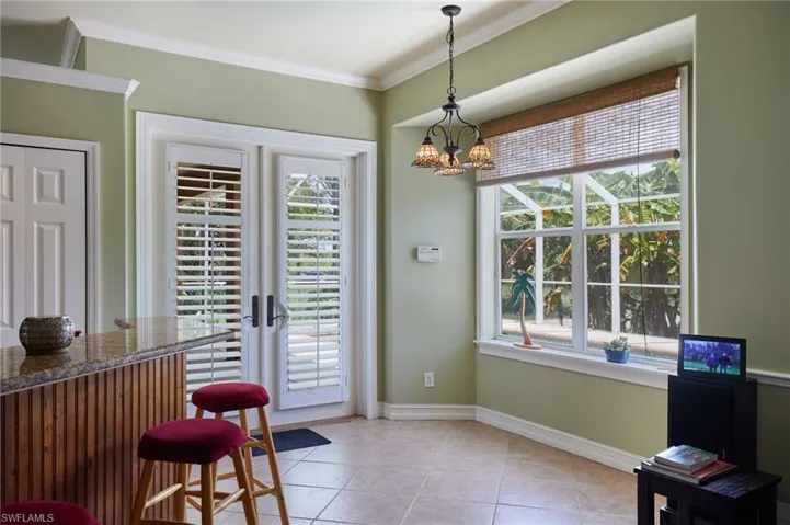 Dining area with crown molding, plenty of natural light, a chandelier, light tile patterned floors, and a dry bar