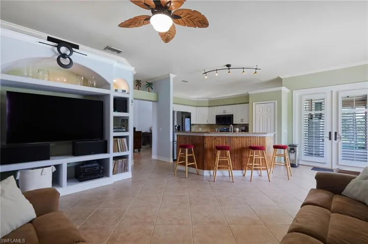 Living area with ornamental molding, light tile patterned flooring, ceiling fan, and rail lighting