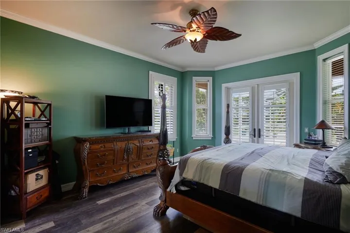 Bedroom featuring dark wood-type flooring, crown molding, a ceiling fan, and access to outside