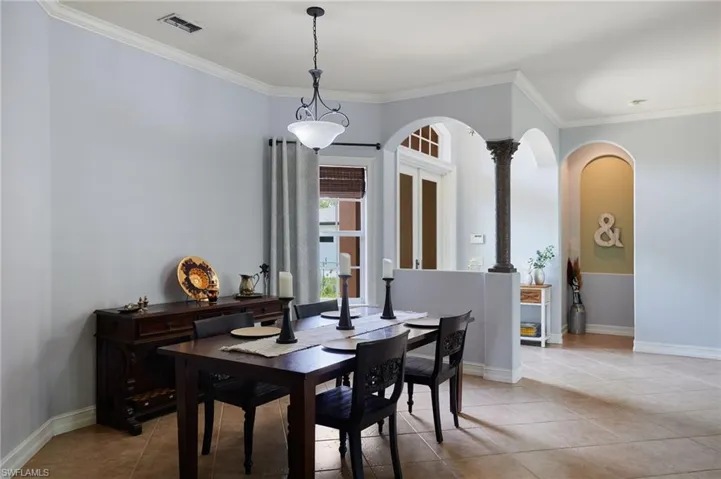 Dining space with ornamental molding, light tile patterned floors, and arched walkways
