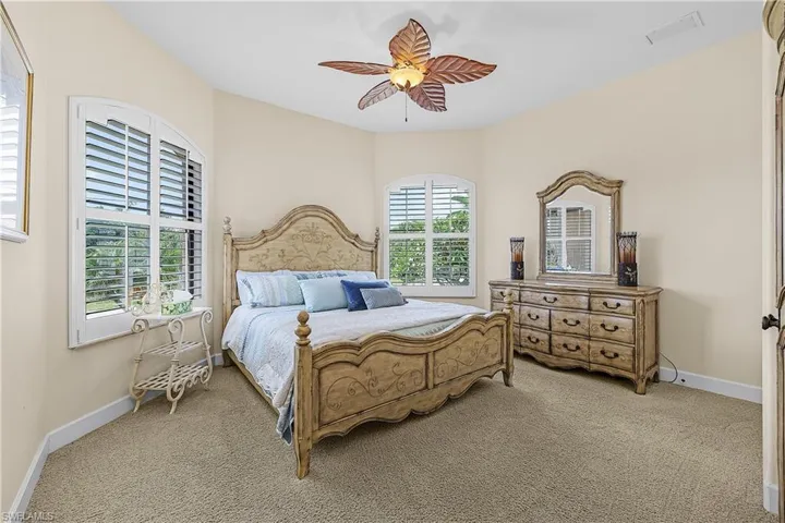 Carpeted room with vaulted ceiling and two arched windows featuring plantation shutters