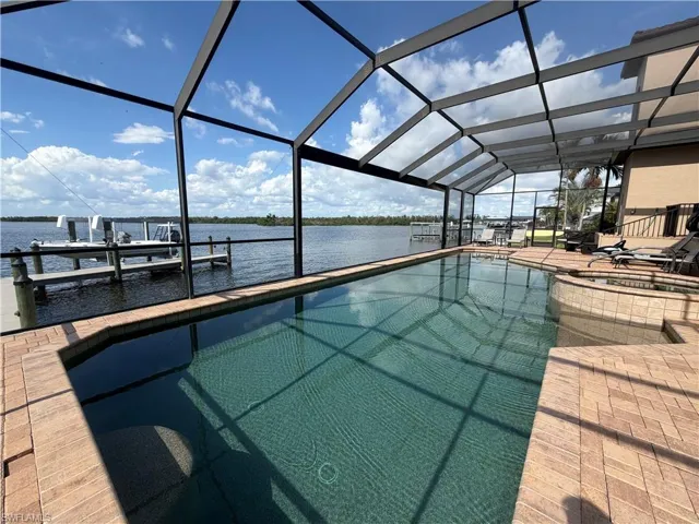 Screened lanai featuring a swimming pool, integrated spa, and brick paver decking