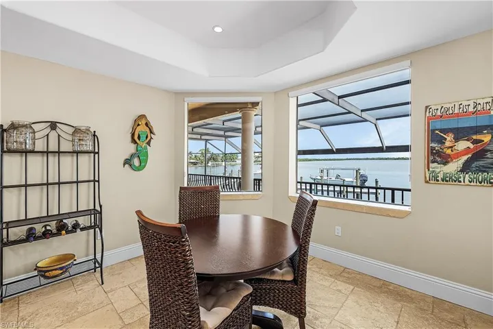 Waterfront dining area with tray ceiling, recessed lighting, and tile flooring