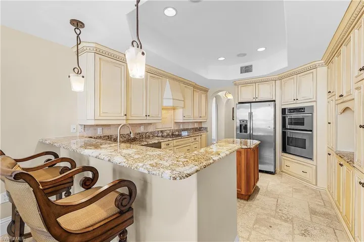 Spacious kitchen featuring extensive cabinetry, stone countertops, stainless steel appliances, a breakfast bar, and tile flooring