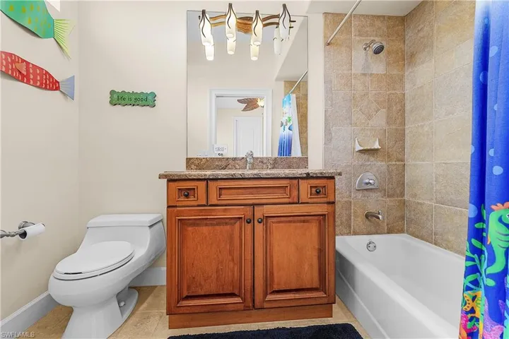 Bathroom featuring a single vanity with a stone-finish countertop, wood-finish cabinetry, and a framed mirror