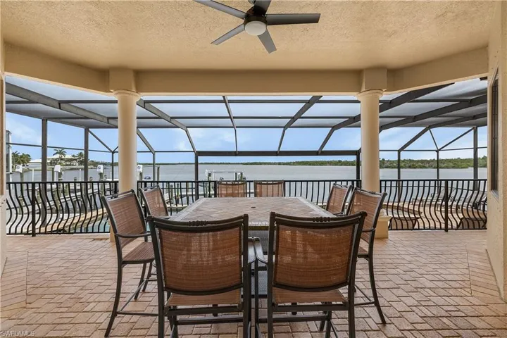 Screened outdoor living area featuring water frontage and decorative iron railings