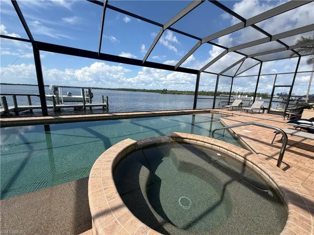 Screened-in outdoor living space featuring a rectangular swimming pool and integrated spa