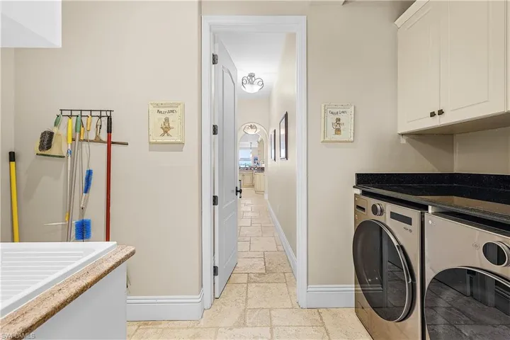 Utility room with neutral-toned walls, tile flooring, and white baseboards