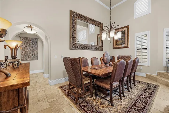 Dining area with a high vaulted ceiling, chandelier lighting, and plantation shutters